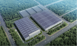 Aerial view of a large industrial park with rectangular warehouses, solar-paneled roofs, and tree-lined roads.